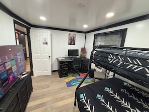 A bedroom with a bunk bed, a desk with a computer, a TV, and a door. - Amazingly located 2 bed 1 bath apart pet friendly (Chattanooga)