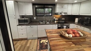 Una cocina moderna con armarios blancos, un microondas, un lavamanos y una encimera de madera.