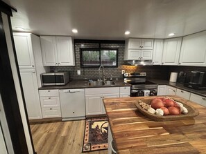 Eine moderne Küche mit weißen Schränken, einer Mikrowelle, einem Spülbecken und einer Holz Arbeitsplatte.
