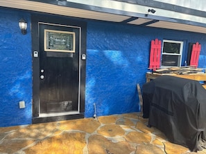 A room with a blue textured wall, a black door with a window, and a covered table with red shutters. - Amazingly located 2 bed 1 bath apart pet friendly (Chattanooga)