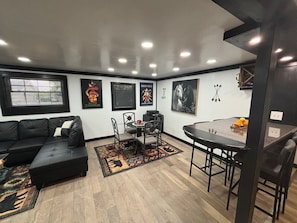 A modern living room with a black sectional sofa, a dining table with chairs, and a rug. - Amazingly located 2 bed 1 bath apart pet friendly (Chattanooga)