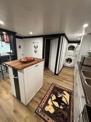 Una cocina compacta con una isla de madera, electrodomésticos integrados y un tapete con diseño de estrellas.