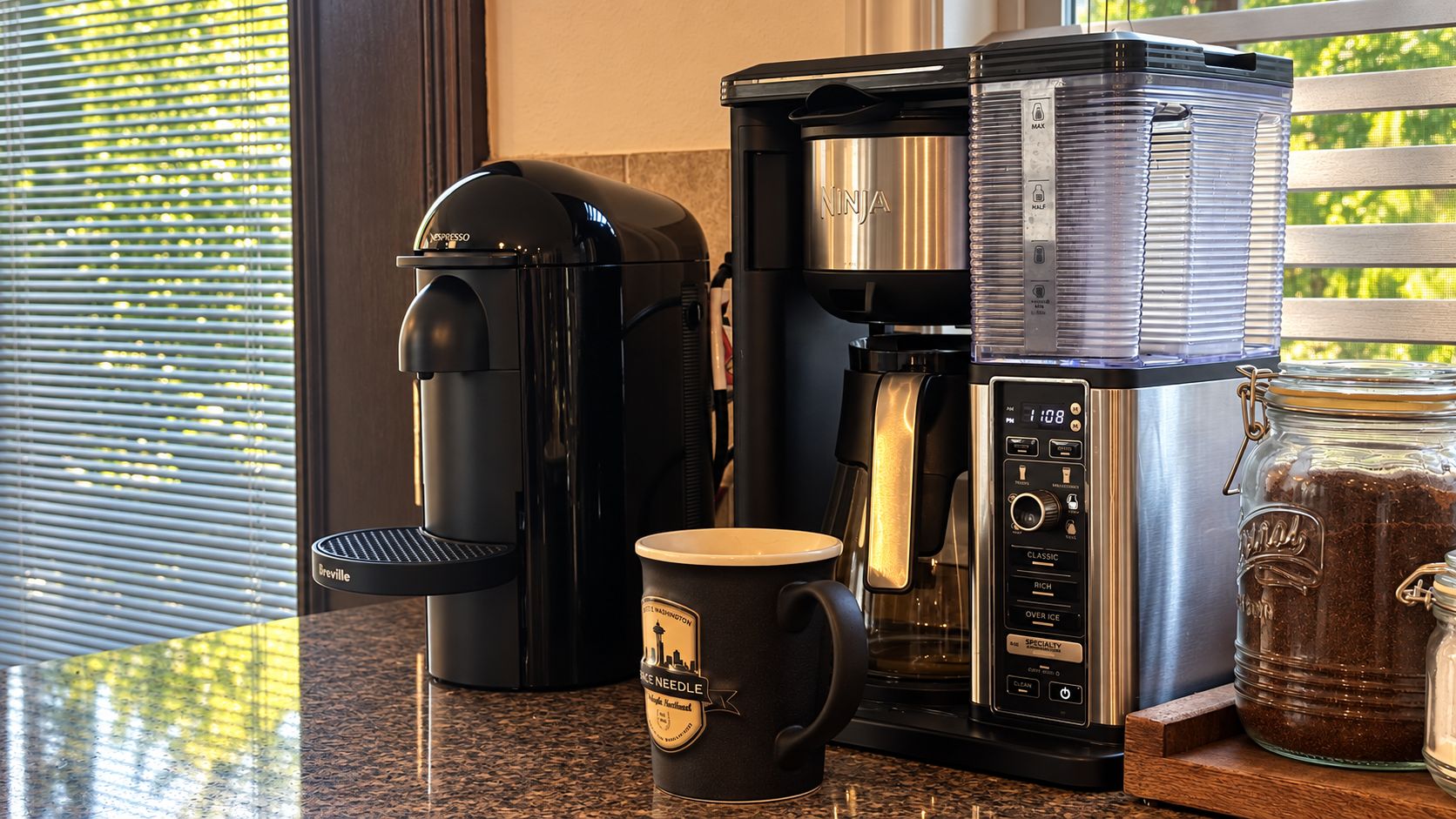 Une machine à café, une tasse et un bocal de café sur un plan de travail de cuisine.