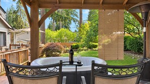 Ein Whirlpool mit Flasche und Glas, umgeben von einer Holzterrasse und Stühlen.