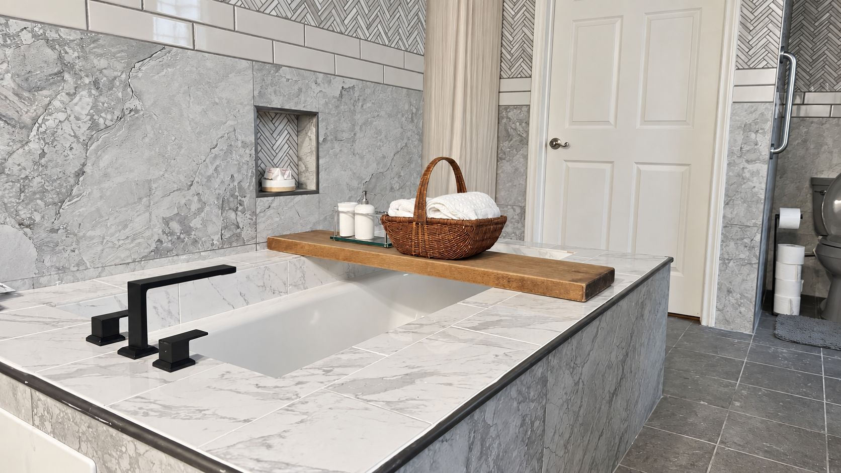 Un baño con un lavabo de mármol, un estante de madera con una cesta, y una puerta blanca.