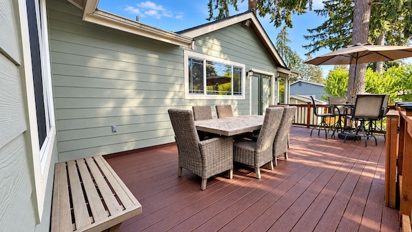 A deck with a table and chairs, a wooden bench, and a patio umbrella.