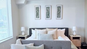 A bedroom with a bed, two bedside tables, a grey sofa, and three wall-mounted art pieces. - Modern Downtown SLC | King Bed + Free Parking (Salt Lake City)