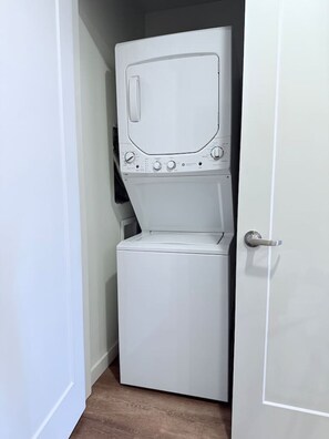 Ein kleiner, weißer Waschraum mit einer Waschmaschine und einem Trockner mit Frontlader, einem Türgriff und einem kleinen Fenster.