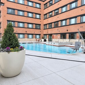 A rooftop pool area with a brick building in the background, a potted plant, and a poolside chair. - Modern Downtown SLC | King Bed + Free Parking (Salt Lake City)