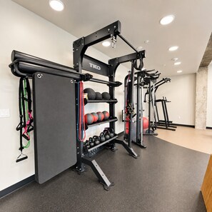 A gym with a TKO weightlifting station, kettlebells, and a treadmill in the background. - Modern Downtown SLC | King Bed + Free Parking (Salt Lake City)