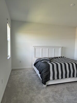 A bedroom with a white headboard, a bed with striped bedding, and a carpeted floor. - New 3BR Townhome in Naples - Resort Pools & Gym (Naples)