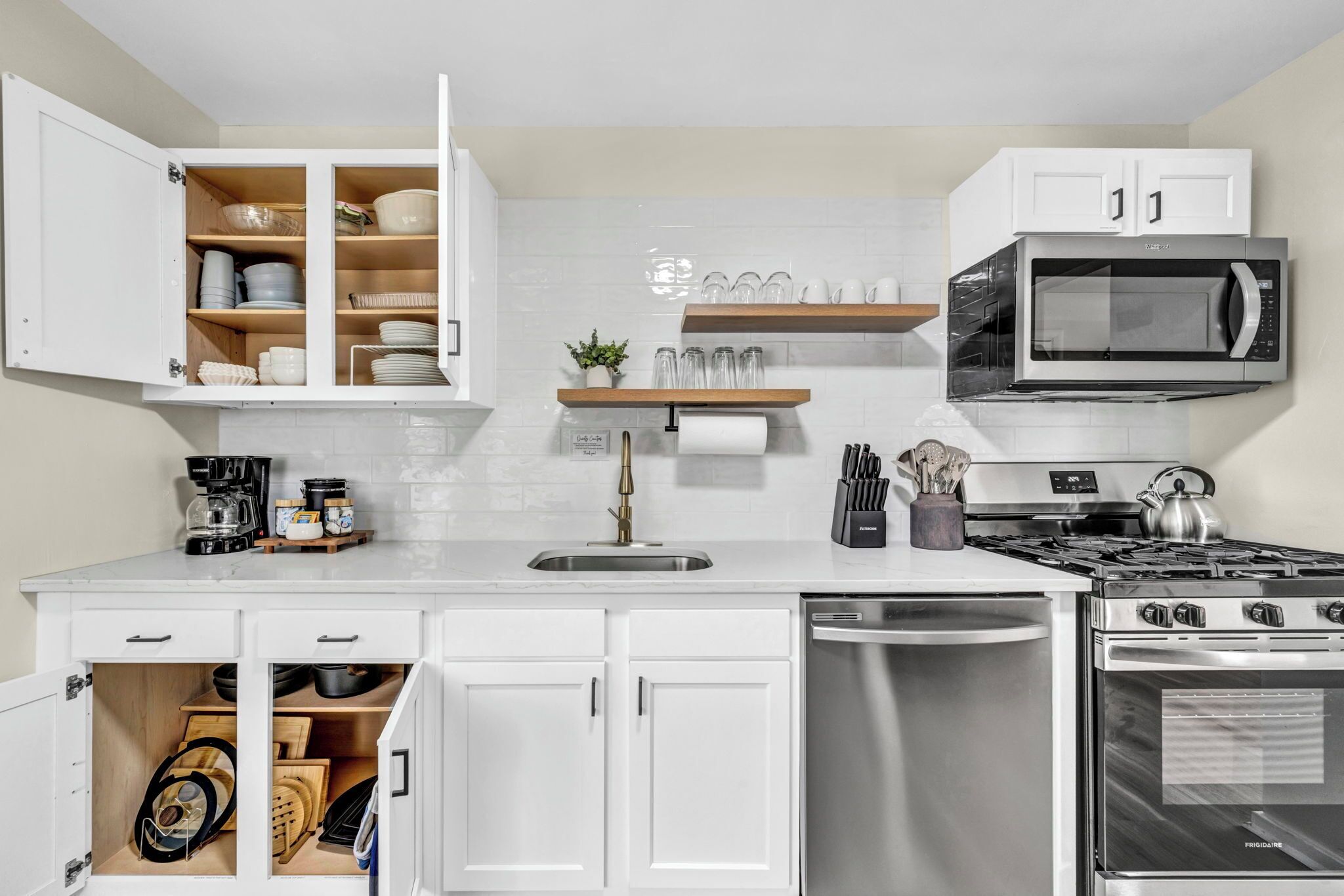 A modern kitchen with white cabinetry, a built-in microwave, a gas stove, and a dishwasher.