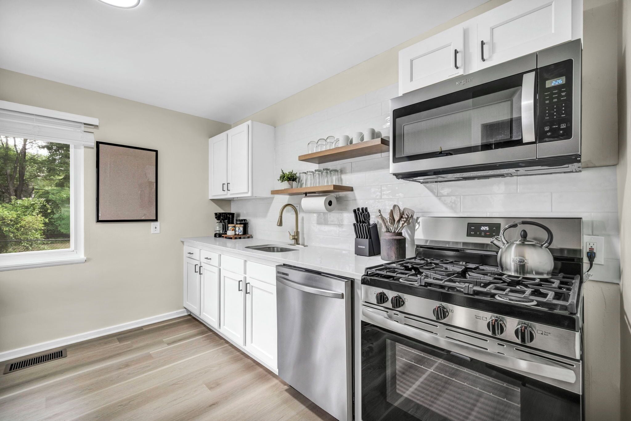 Une cuisine moderne avec des meubles blancs, une cuisinière en acier inoxydable et un four à micro-ondes.