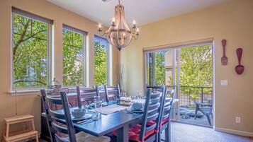 A dining room with a large table set for six, surrounded by chairs.