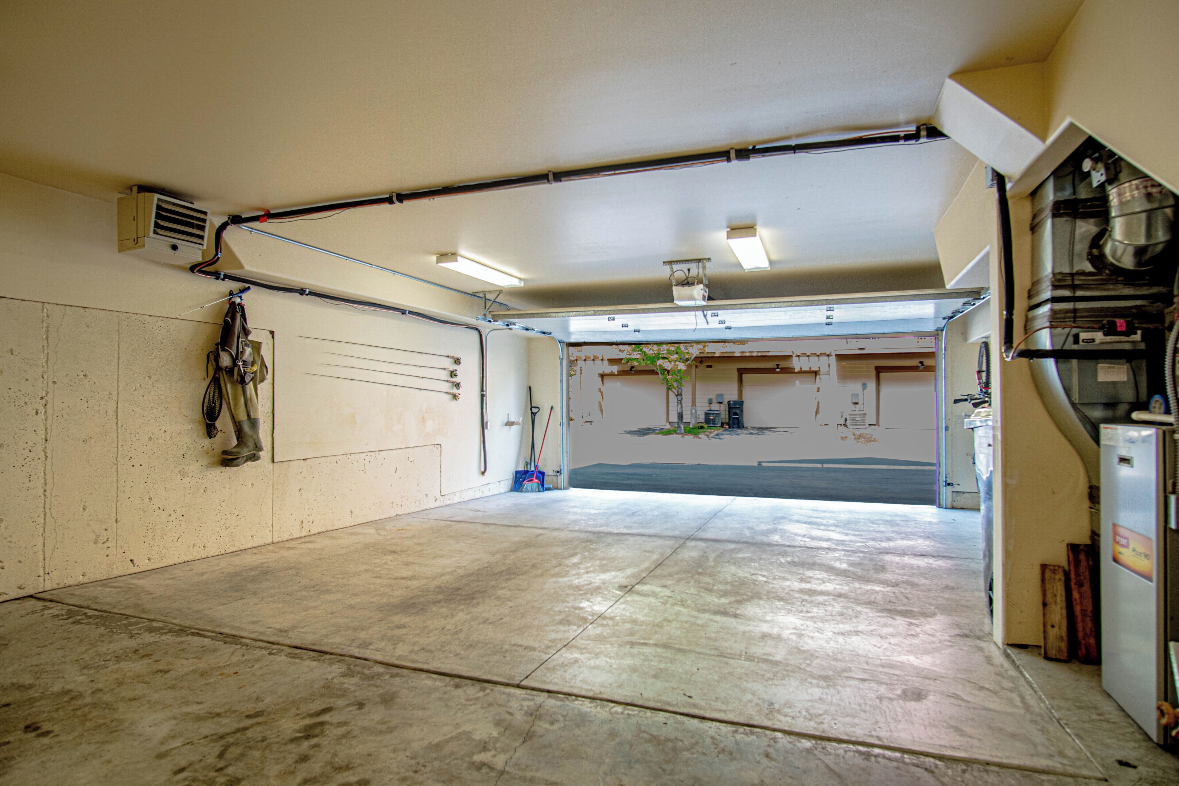 A garage with a concrete floor, a workbench, and a door leading to a driveway.