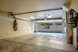 Een garage met een betonnen vloer, een werkbank en een deur naar een oprit.