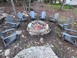 A circular seating arrangement around a central fire pit with rocks, surrounded by trees. - The Totteridge (Saw Creek)