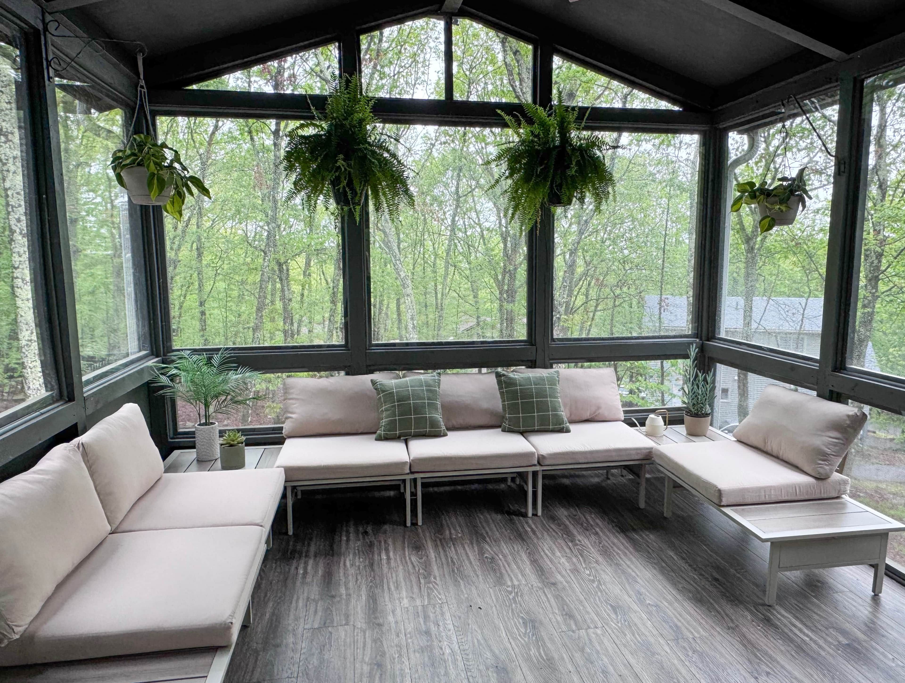 A conservatory with a built-in bench seating area, large windows, and hanging plants.