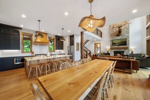 A spacious kitchen with a central island, wooden bar stools, and a dining table. - Stunning Mountain Retreat with Views & Hot Tub (Banner Elk)