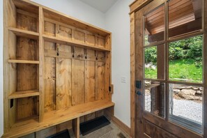 Eine eingebaute Holzbank mit Haken, eine Tür mit Glasfeldern und ein Steinweg vor der Tür.