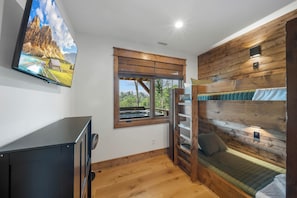 A room with a bunk bed, a television mounted on the wall, and a window with a view of a mountain landscape. - Stunning Mountain Retreat with Views & Hot Tub (Banner Elk)
