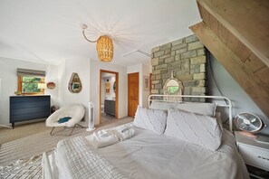 Ein Schlafzimmer mit Bett, Sessel, Nachttisch, Lampe und Deckenventilator.