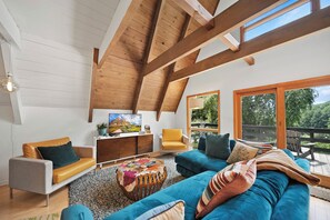 A spacious living room with a high ceiling, wooden beams, a television, and a view of the outdoors. - Private Mountain Getaway Near Boone with Hot Tub (Vilas)