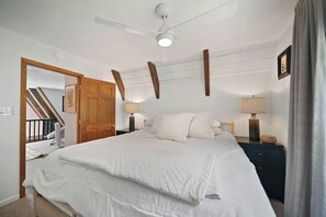 A bedroom with a large bed, two bedside tables with lamps, a ceiling fan, and a wooden door. - Private Mountain Getaway Near Boone with Hot Tub (Vilas)