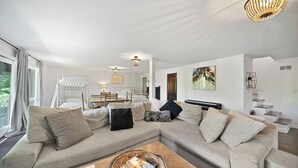 Ein modernes Wohnzimmer mit einem Ecksofa, einem Couchtisch und einem Essbereich mit Tisch und Stühlen.