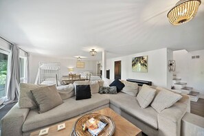 Ein modernes Wohnzimmer mit einem Ecksofa, einem Couchtisch und einem Essbereich mit Tisch und Stühlen.