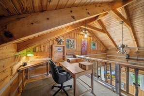 Ein Dachzimmer aus Holz mit Schreibtisch, Stuhl und Blick ins Freie.