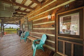 A wooden cabin with a porch, numbered 129, featuring a bench and chairs, and a view of the outdoors. - Secluded Mountain Escape with Incredible Views (Banner Elk)