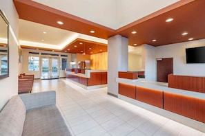 A modern reception area with a reception desk, seating, and a flat-screen TV.