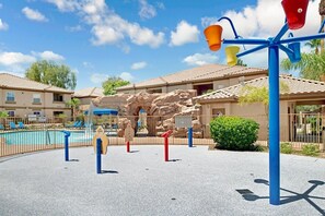 Un área de juegos con piscina, una formación rocosa y un edificio con tejado de azulejos.