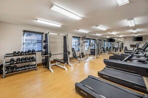Un gimnasio con cintas de correr, máquinas de pesas y mancuernas.