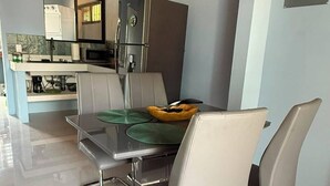 Une cuisine moderne avec un coin repas, comprenant un réfrigérateur en acier inoxydable, un four à micro-ondes et une table à manger avec des chaises.
