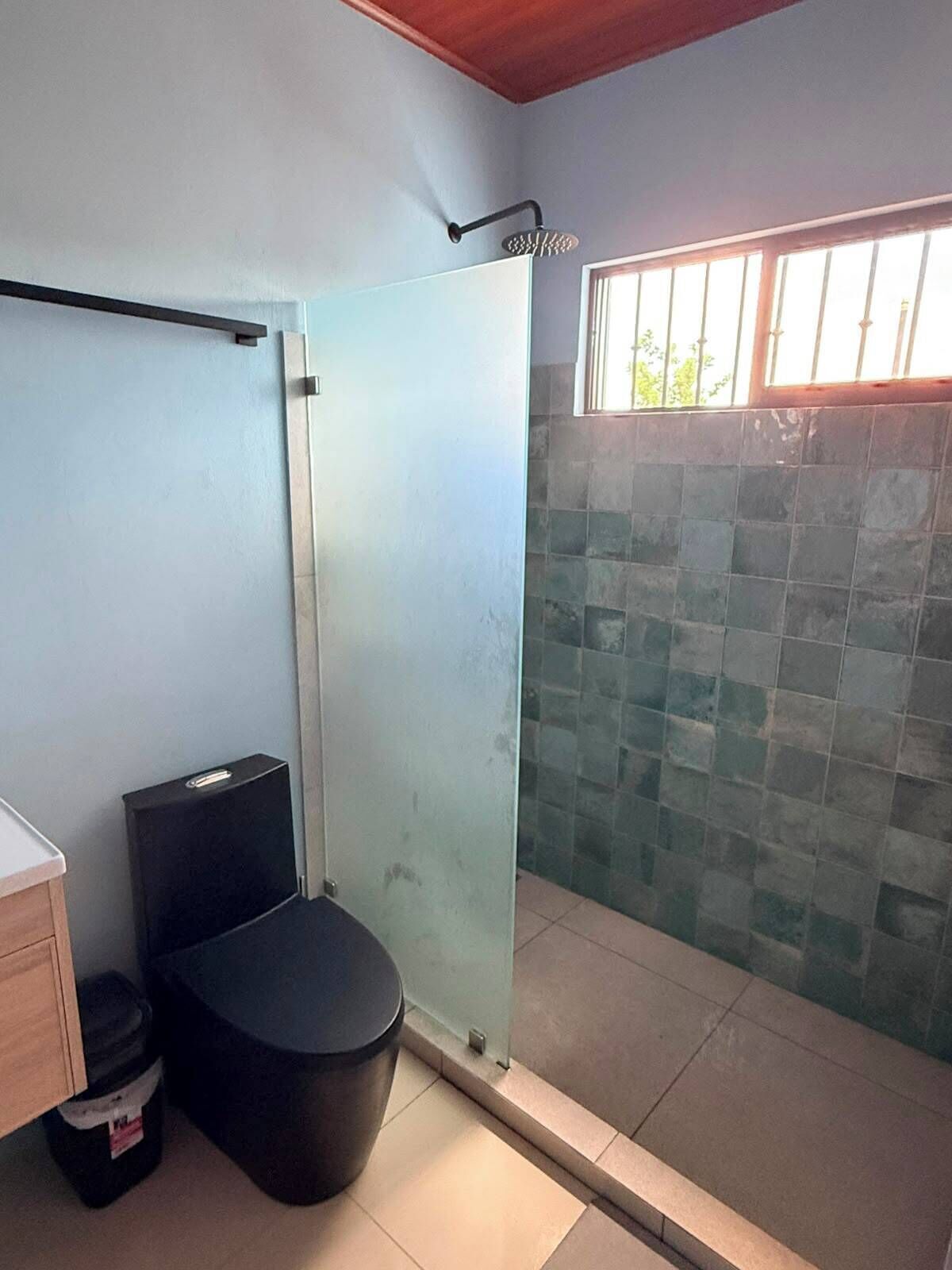 Een kleine badkamer met een douche, toilet en een klein afvalbakje.