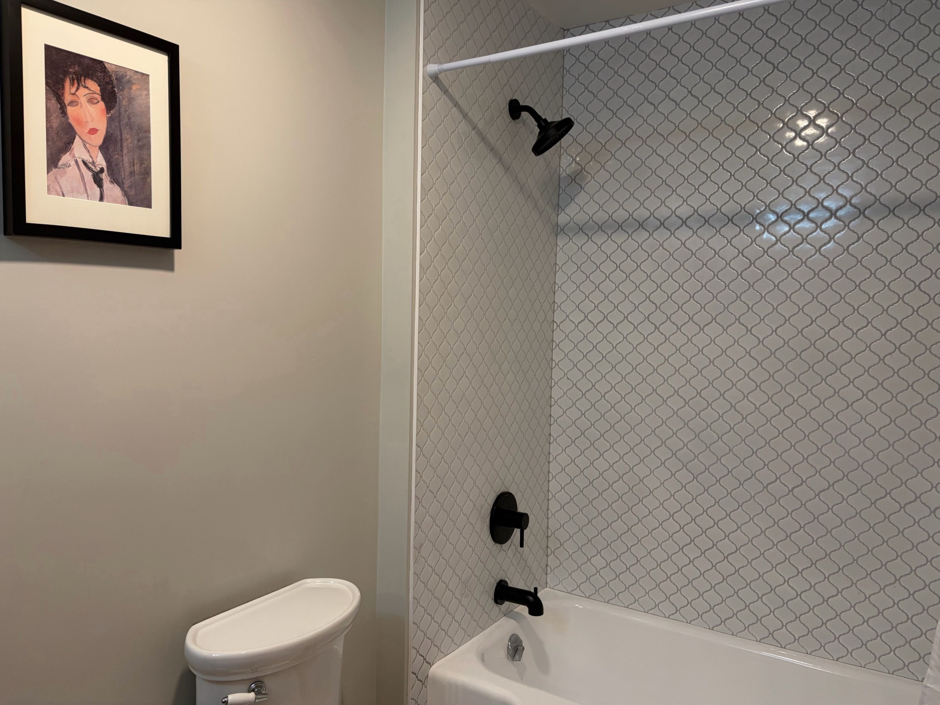 A bathroom with a toilet, a shower with a black faucet, and a sink.