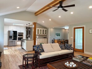 A spacious living area with a sofa, coffee table, and a dining area in the background.