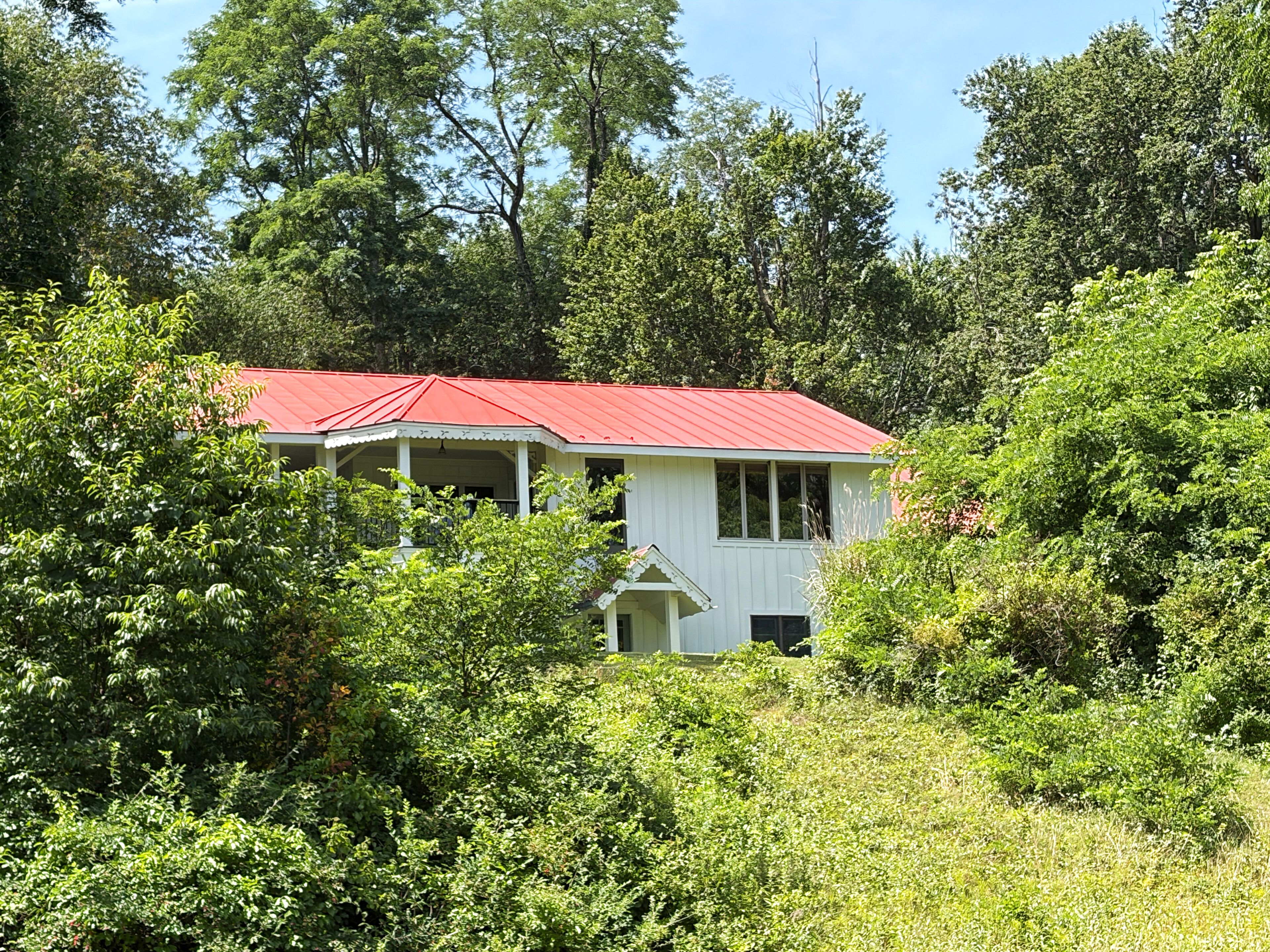 Ein weißes Gebäude mit rotem Dach, umgeben von üppiger Vegetation.
