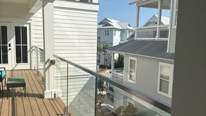 A wooden deck with a glass balustrade overlooking a residential area. - Dune Manor 124-Pool + Rooftop Deck-Sleeps 16 (Seagrove Beach)
