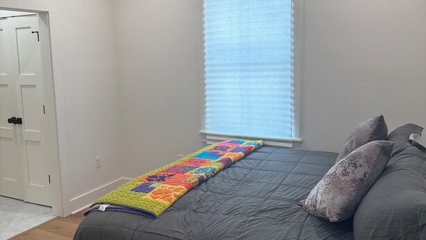 A bedroom with a bed, a ceiling fan, a window with blinds, and a door. - Dune Manor 124-Pool + Rooftop Deck-Sleeps 16 (Seagrove Beach)