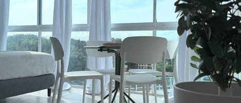 Una habitación con una cama, una mesa con una planta y vistas al exterior a través de amplios ventanales.