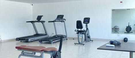 A gym with treadmills, a rowing machine, and weight equipment.