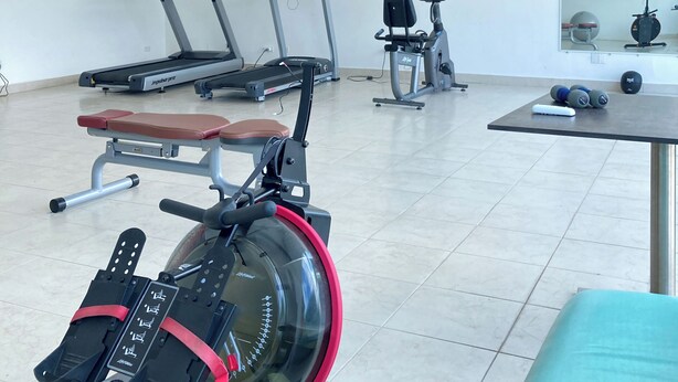 A gym with treadmills, a rowing machine, and weight equipment.