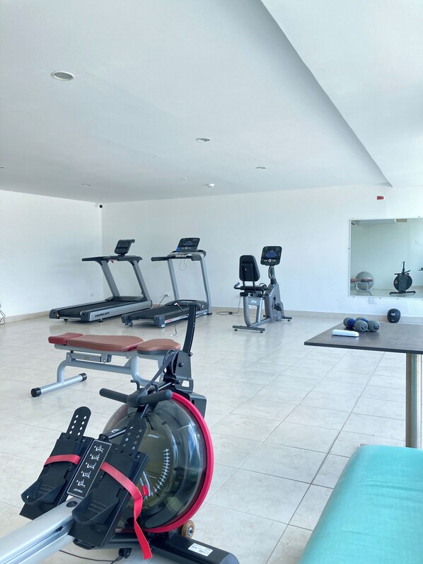 A gym with treadmills, a rowing machine, and weight equipment.