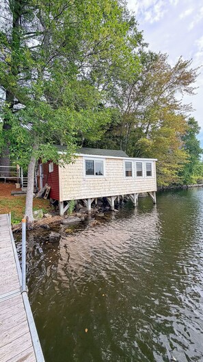 A houseboat with a wooden exterior, windows, and a dock.