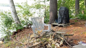 A campsite with a white chair, a black tarp, and a pile of branches. - Glamping in the Lake - Ovah to Camp! (Manchester)