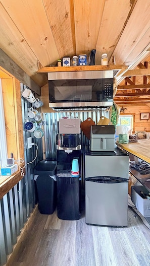 A compact kitchen with a microwave, refrigerator, and water dispenser. - Glamping in the Lake - Ovah to Camp! (Manchester)