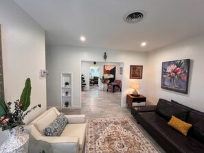 Ein Wohnzimmer mit einer Couch, einem Couchtisch, einem gemusterten Teppich und einem Bild an der Wand.